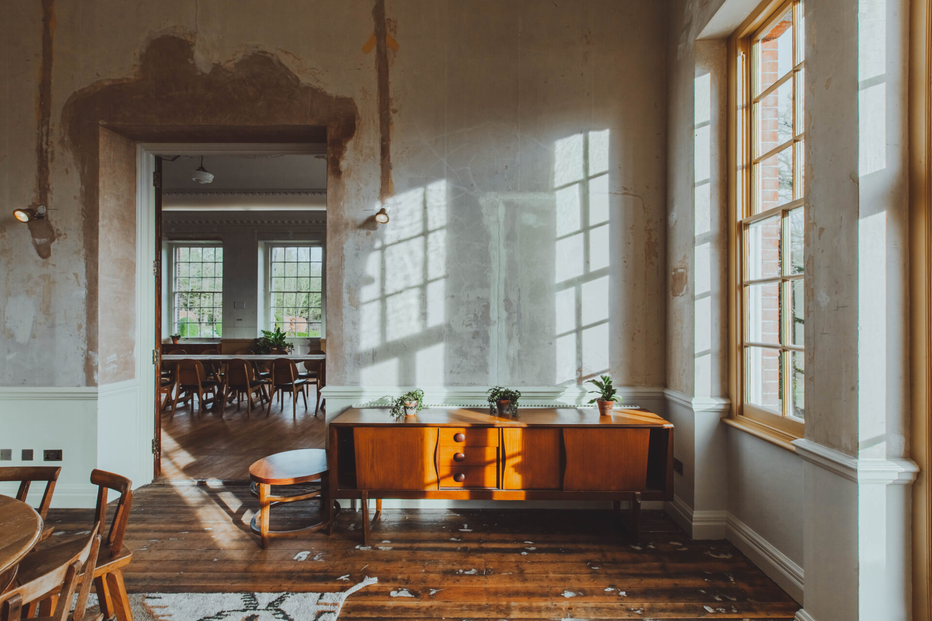 Where to co-work in London | Sunlight streams into a white-washed room with wooden flooring and antique wooden furniture at Birch Community