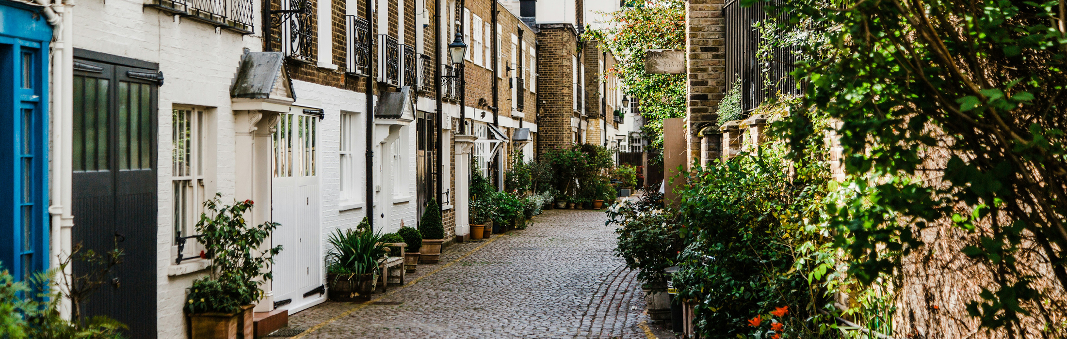 A cobblestone street lined with lamp posts and greenery in London