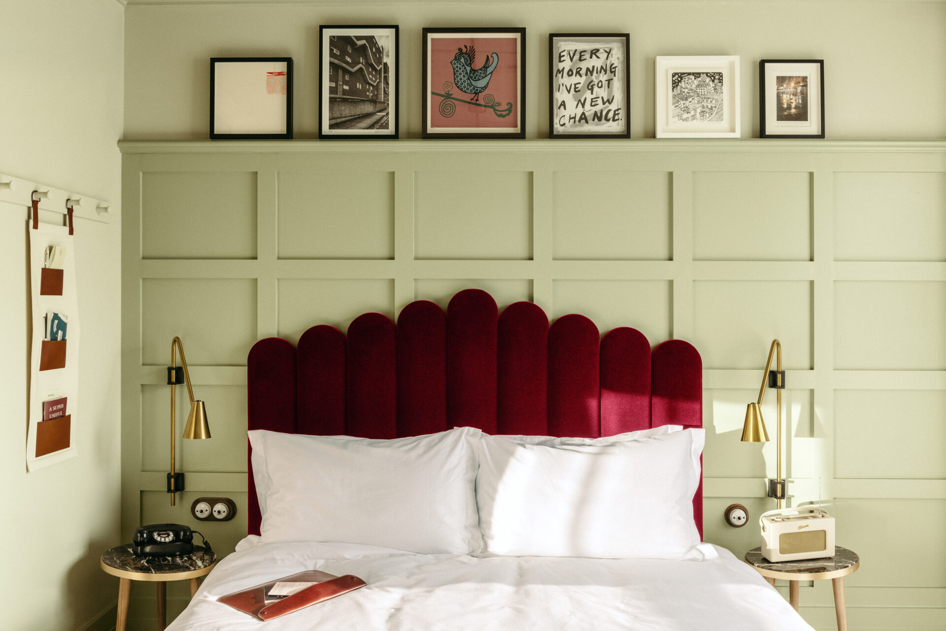 A white-sheeted bed with a ruby-red velvet headboard in front of a mint green wall at The Hoxton Southwark