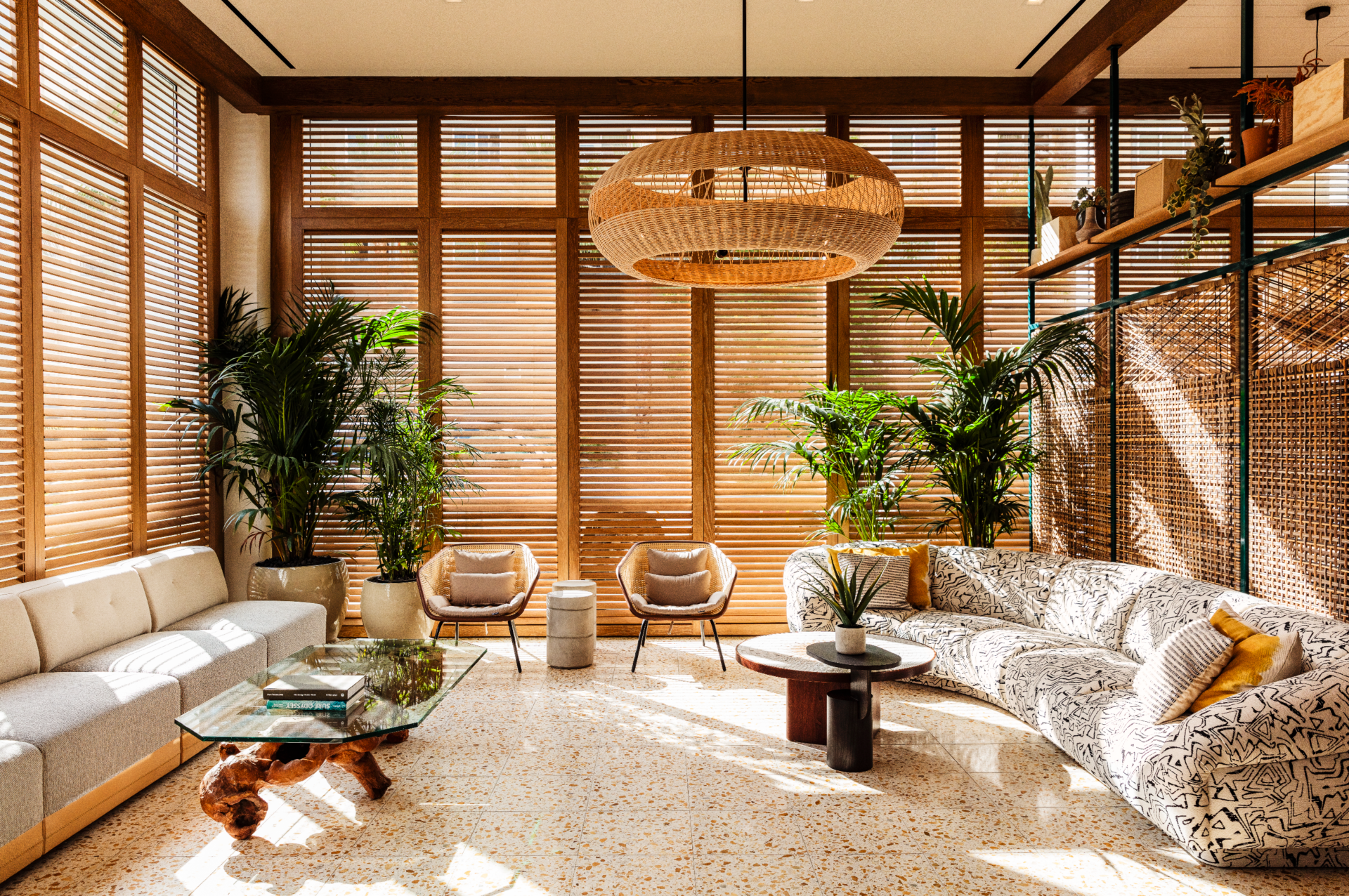 The best places to stay in LA | An interior view at The Hotel June. Wooden blinds cover the windows, a rattan light shade hangs from the centre of the ceiling, and two sofas flank the lounge on either side