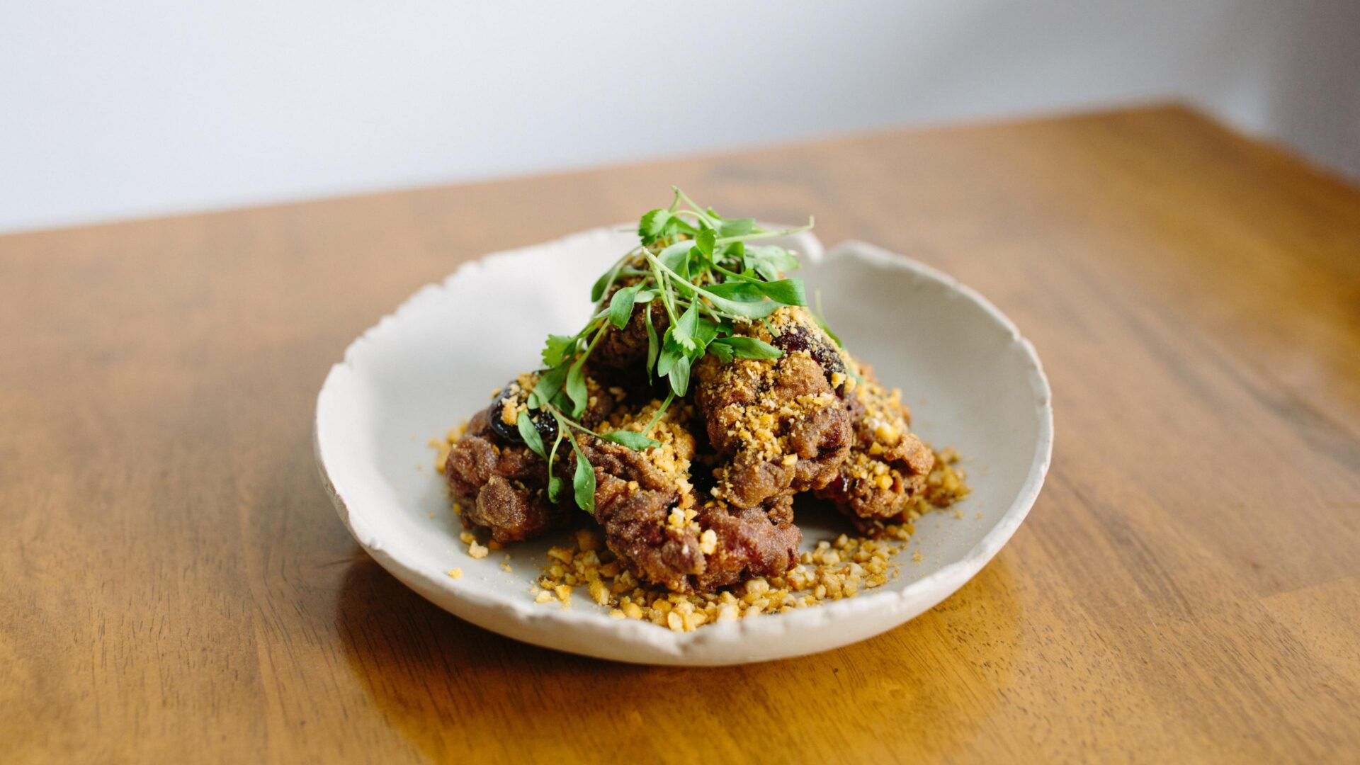London's best restaurants | a bowl on a wooden table containing James Cochran's signature buttermilk fried chicken dish, with his famous scotch bonnet jam