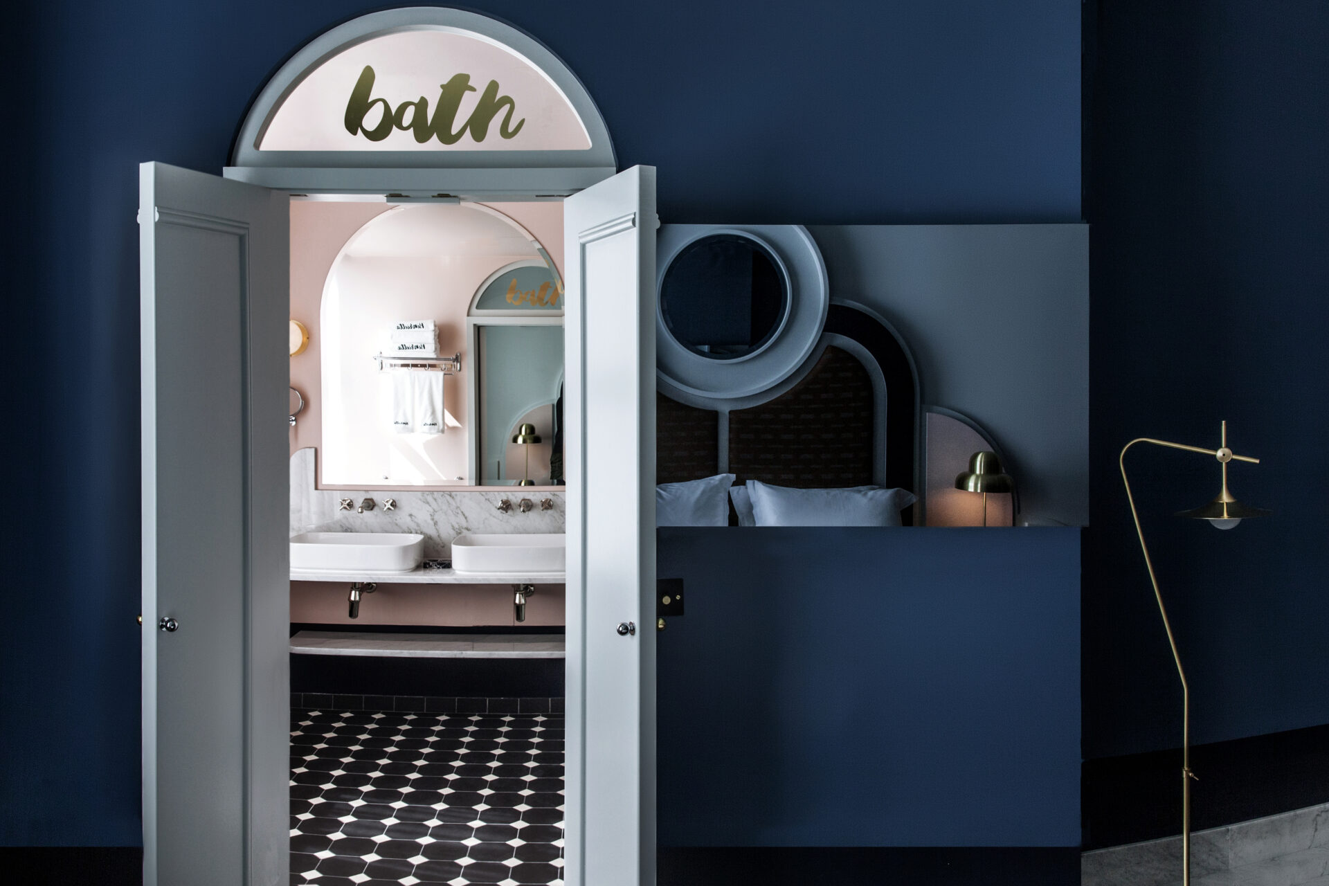 Best hotels in London | an arched doorway in a dark blue wall that looks into a bathroom with a black-and-white-checked floor at the Henrietta Hotel in Covent Garden