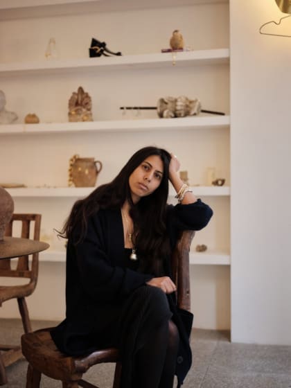 Rosh Mahtani, Alighieri | the designer wearing head-to-toe black in front of some shelves in her studio