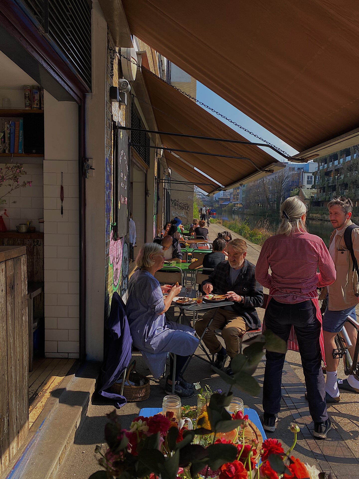 Local's guide to London | Towpath Cafe on Regent's Canal, with people sitting at tables under awnings along the side of the water