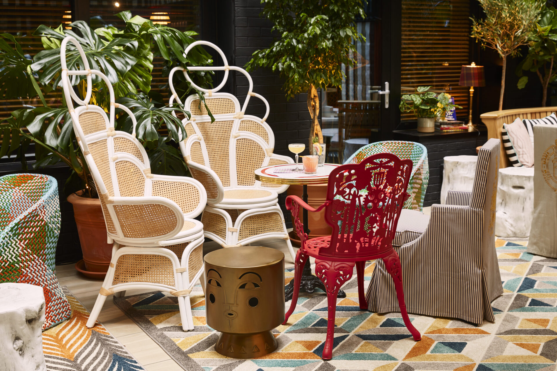 A view of the courtyard at Mama Shelter in Shoreditch, London. A mismatched assortment of chairs are arranged around a table, and multi coloured tiles decorate the floor.