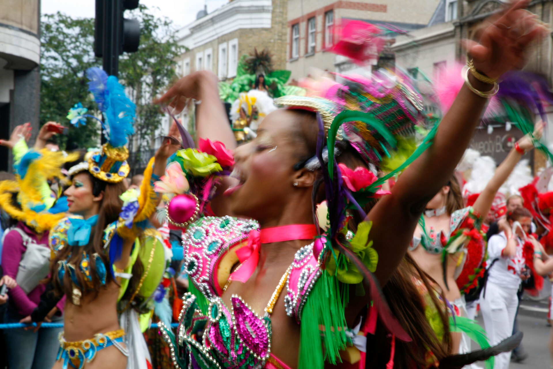 London's Caribbean community | A woman wearing a vibrant pink-and-green costume dancing in a parade at London's Notting Hill Carnival