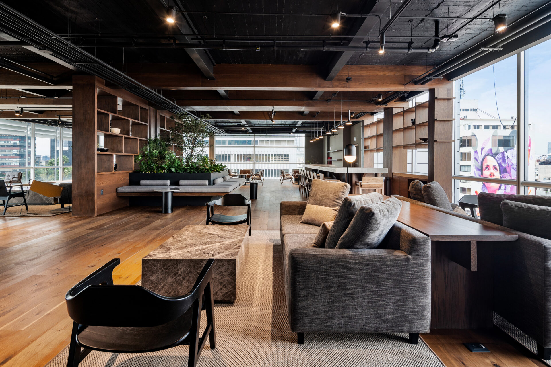 sleek sofas and chairs in a spacious open-plan room with wooden floors and floor-to-ceiling windows