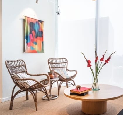 wicker furniture in front of a white wall with a colourful painting at WeWork in Insurgentes Sur