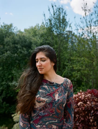 An interview with poet Nikita Gill | A portrait of poet Nikita Gill, wearing a paisley patterned dress, and sat outside