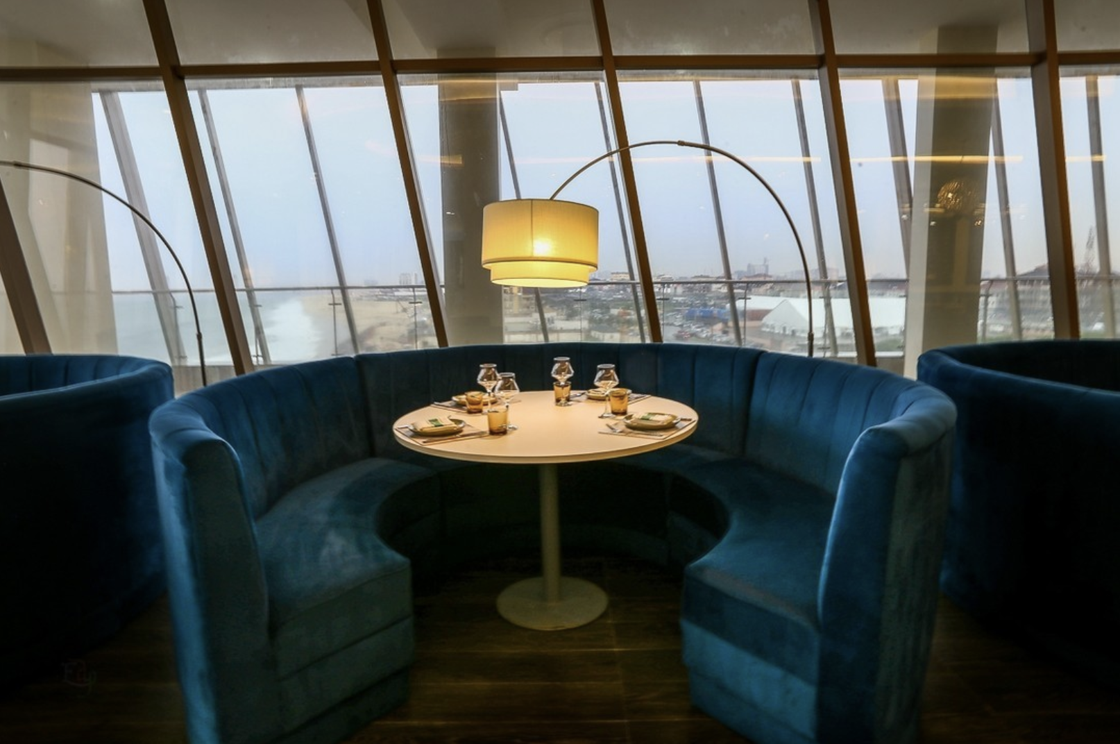 Cosy blue banquet seating surrounding a circular table by a window at 788 on the Sea, Lagos