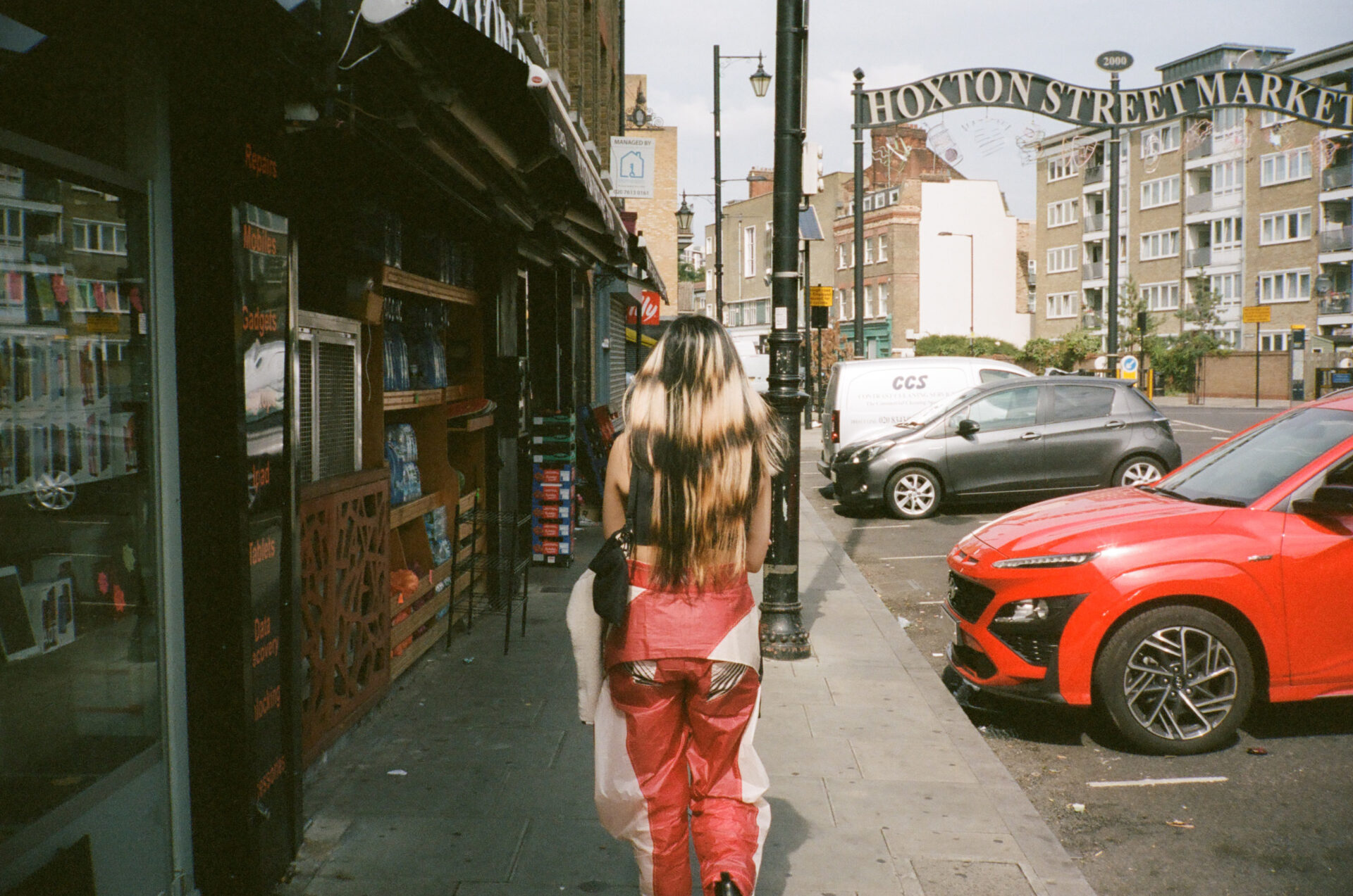 An interview with Thai pop singer Pyra | Pyra walking away from the camera towards a metal Hoxton Street Market sign curving above the road.