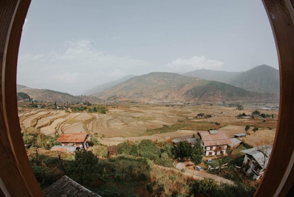 Bhutan reopens its borders | mountaintops and fields under a pale blue sky