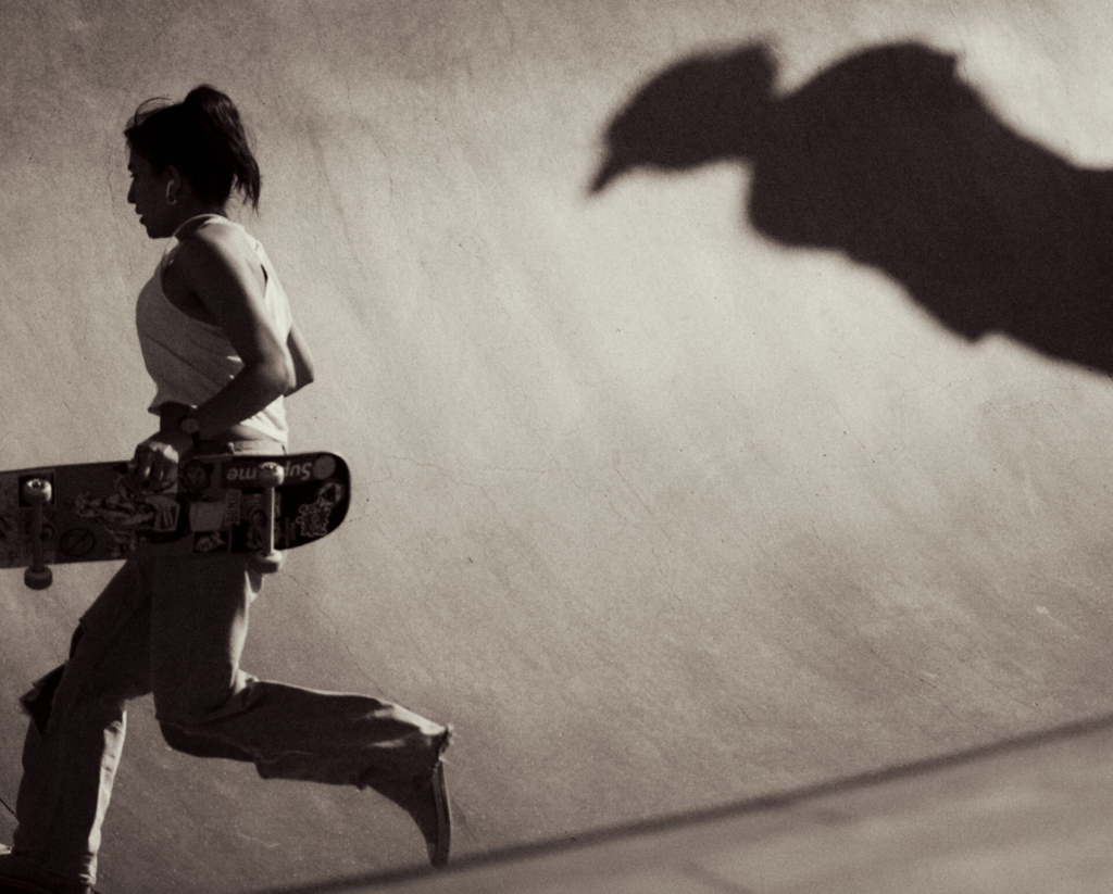 Focal Point, Erik Melvin | A skater runs with her board in her hand, while a shadow of another skater is cast on the wall behind her. Photo by Erik Melvin