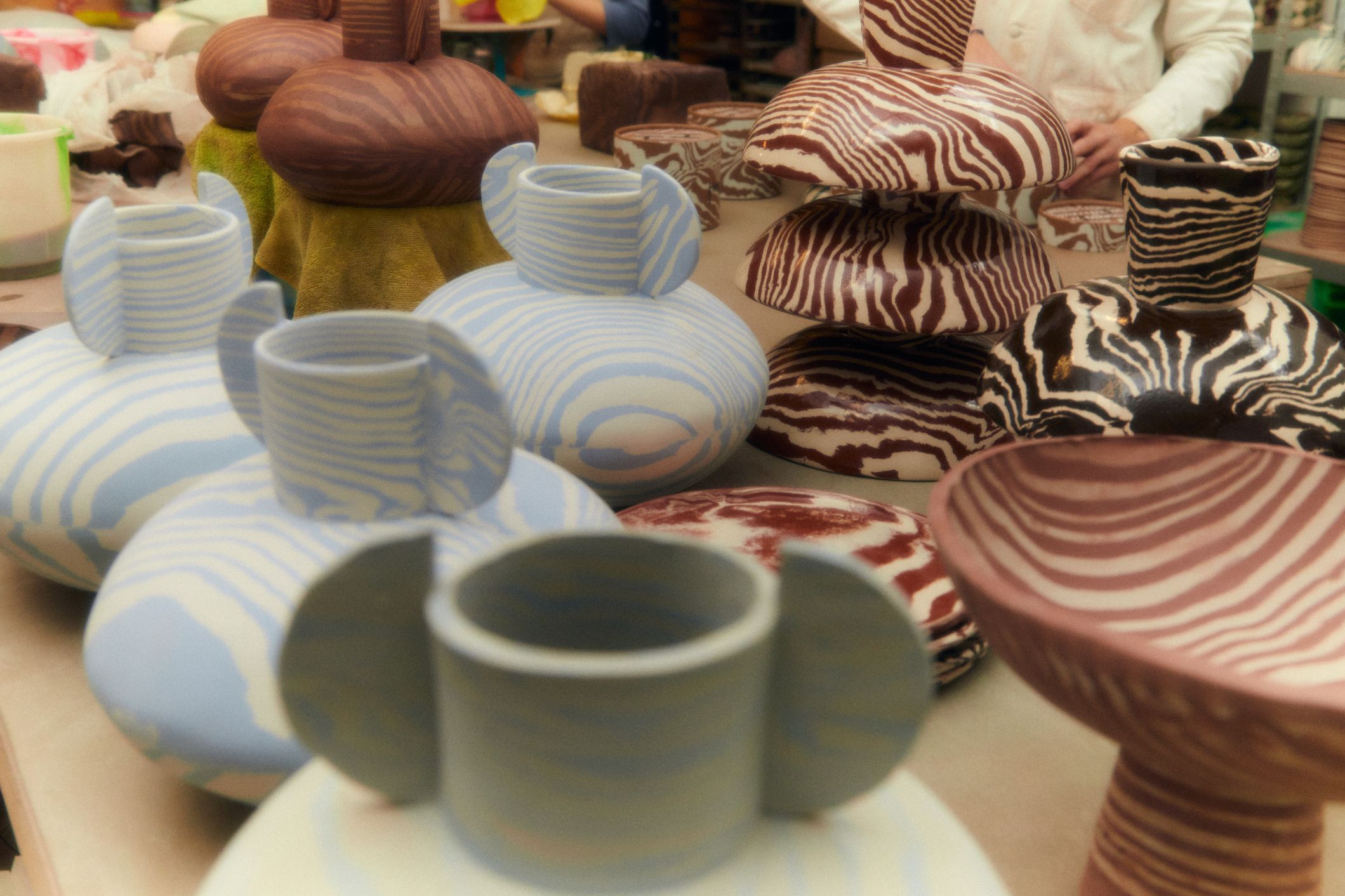 In the studio with Henry Holland | Vases and bowls at various stages of firing on a workbench in the studio.