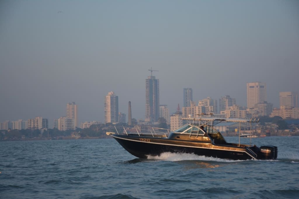 A weekend guide to Alibaug | A speed boat travels from right to left past the skyline of Mumbai in the background