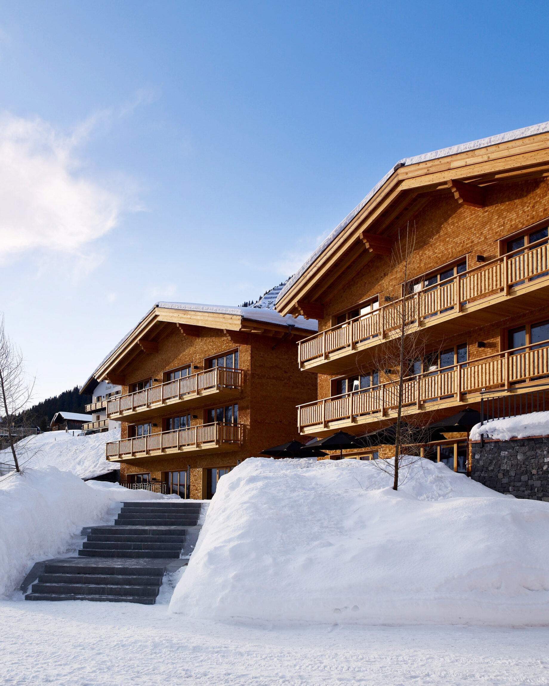 The most spectacular places to stay in the Alps this winter | The two pitched roofs of Hotel Aurelio and its chalet in the sun with snow outside