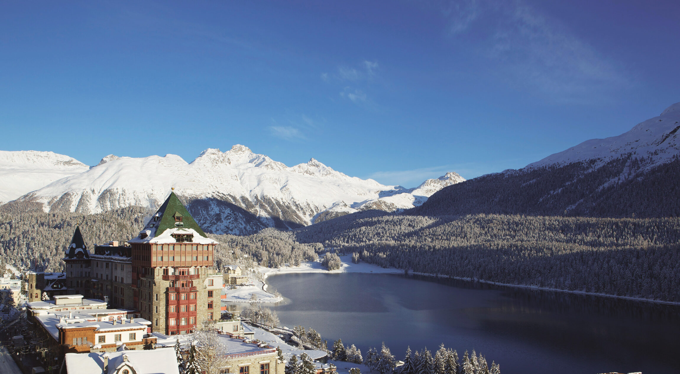 Badrutt's Palace overlooking Lake St Moritz, with a snowy mountain in the background