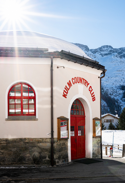 Red lettering at the The Kulm Hotel St. Moritz Club against an alpine backdrop