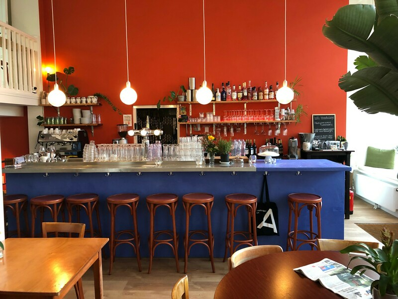 The best co-working spaces in Amsterdam for remote working | Blue bar with brown stools in front of a red painted wall.