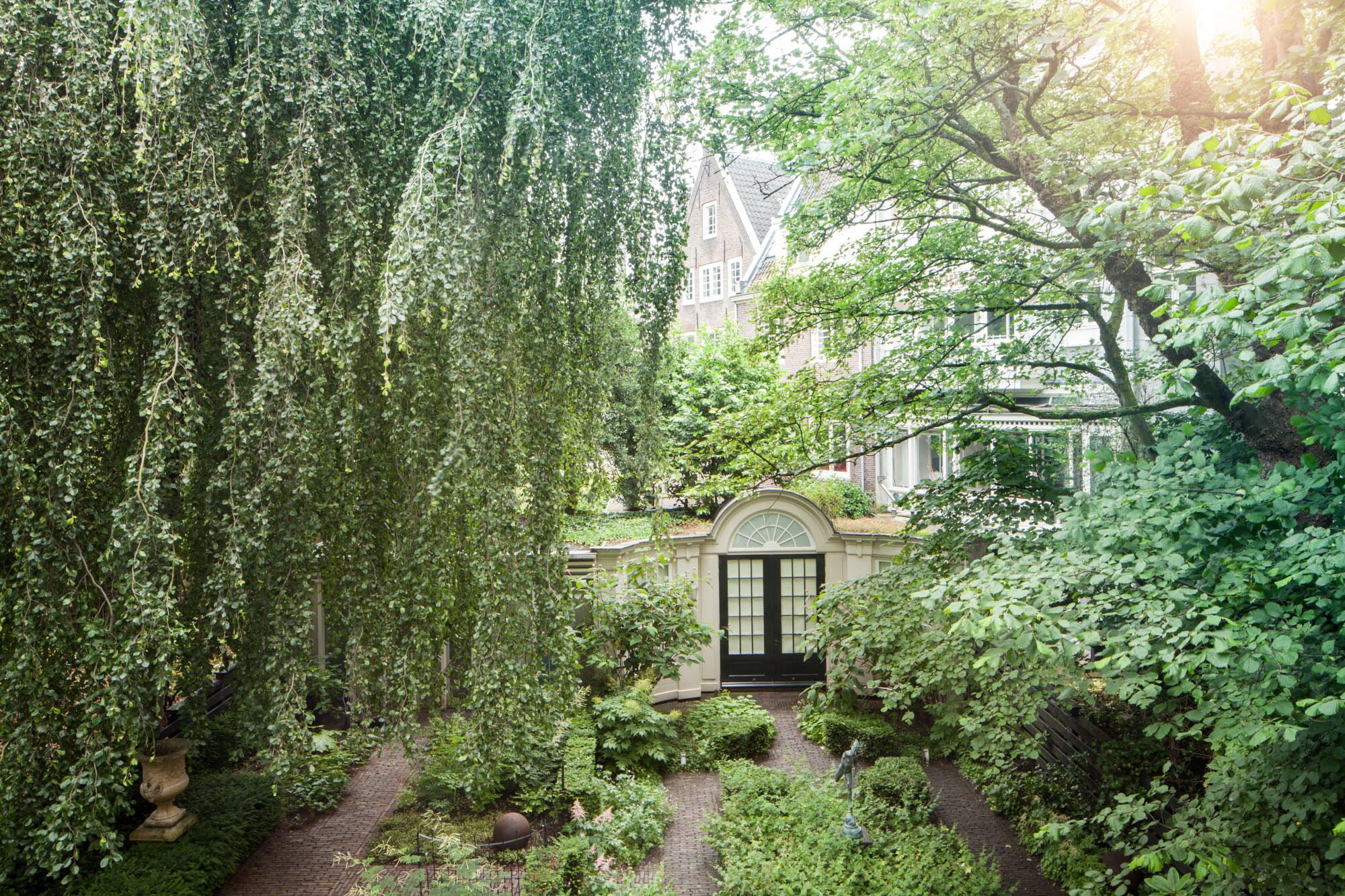 Greenery covering a gate leading to a large building.