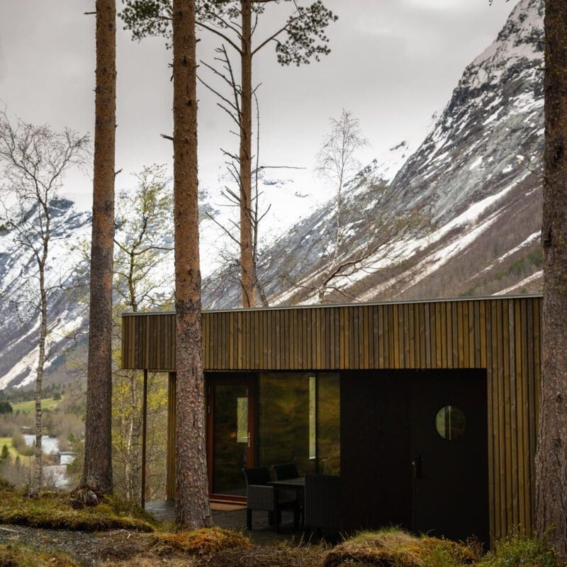 Hotel Wellness | Writers lodge in a field of green moss with a snowy mountain in the background