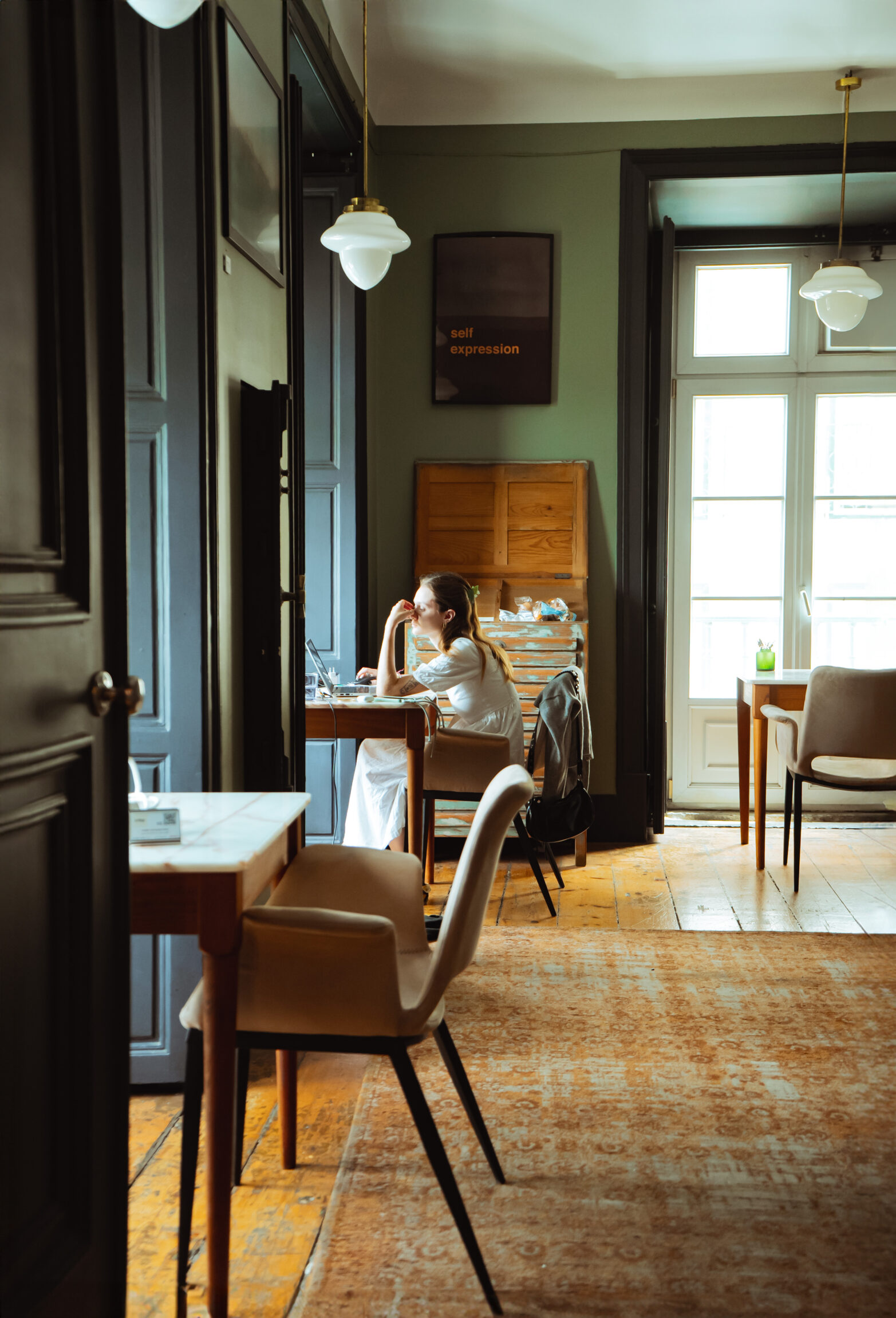 A person works at a desk in a window in a large room at Tribe Social Club.