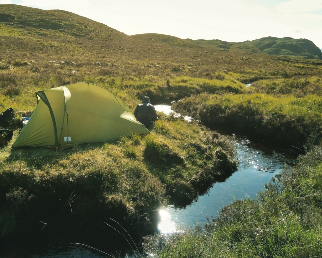 A tent pitched by a stream.