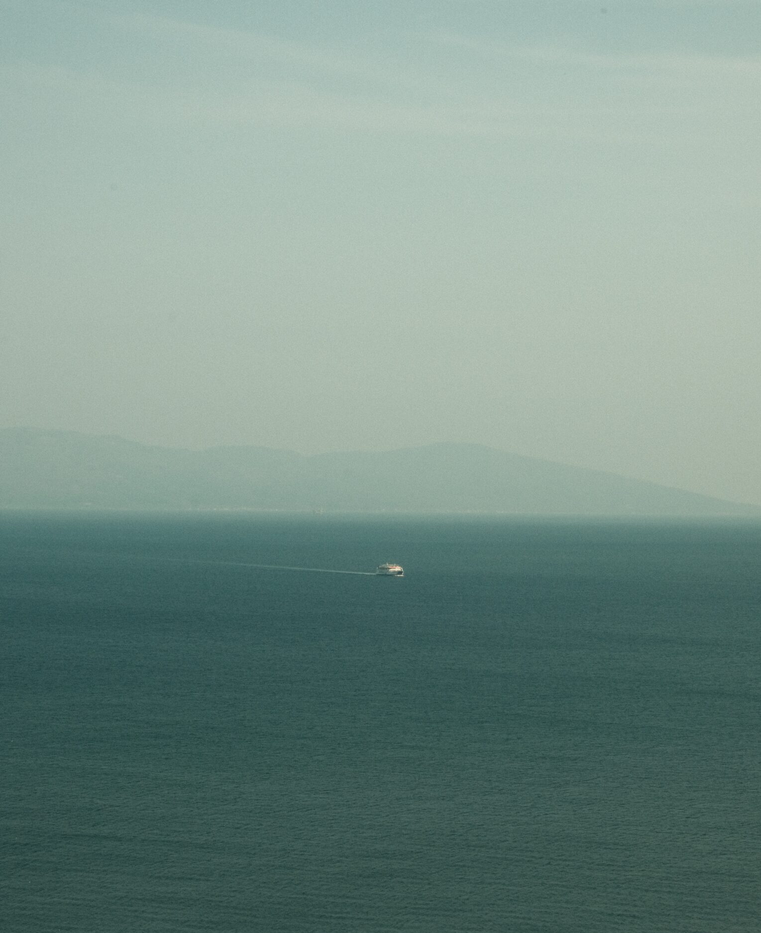 Sustainability and ferry boats | A ferry boat in the distance in the sea on a misty day