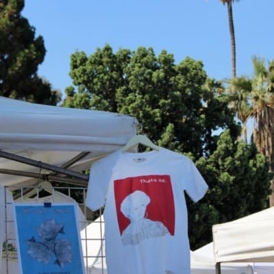 A T-shirt hung on a stall in front of a palm tree at Melrose Trading Post flea market