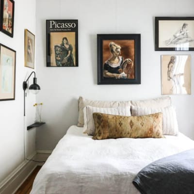 The best places to stay in Hudson | A wall of art above a bed at This Old Hudson Farmhouse