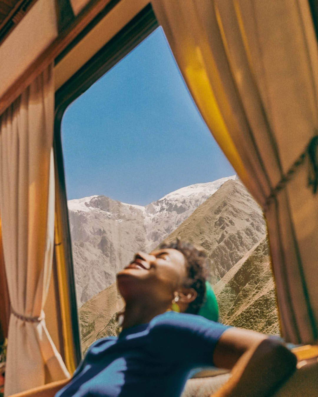 A woman against a snow-capped mountain aboard a Belmond train