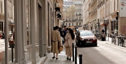 Two people strolling down a traditional Parisian street alongside vintage shop Thanx God I'm a VIP