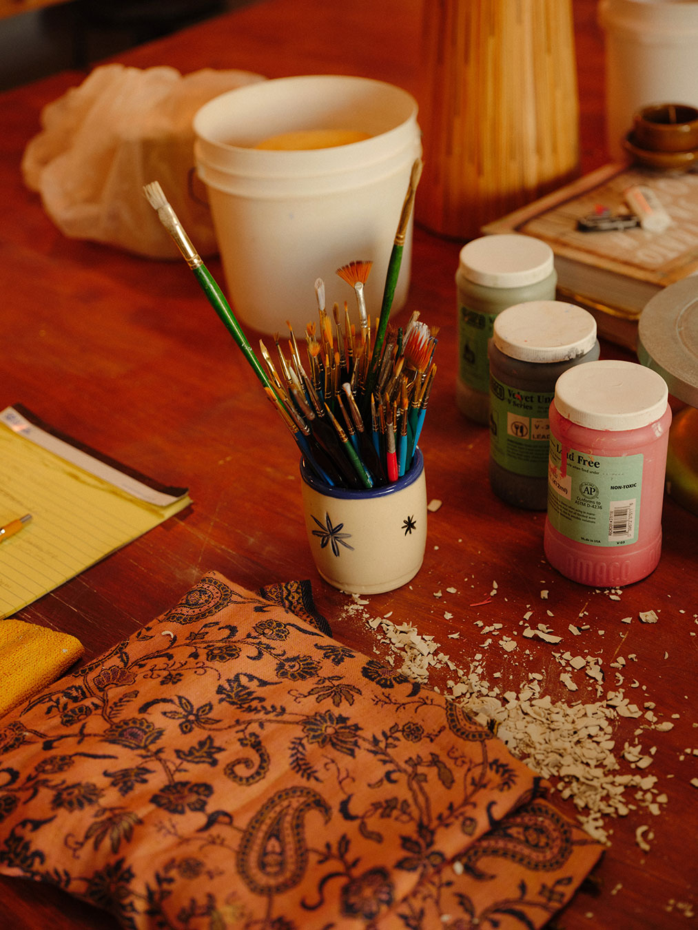 A detail of paint brushes on a workbench in the studio.