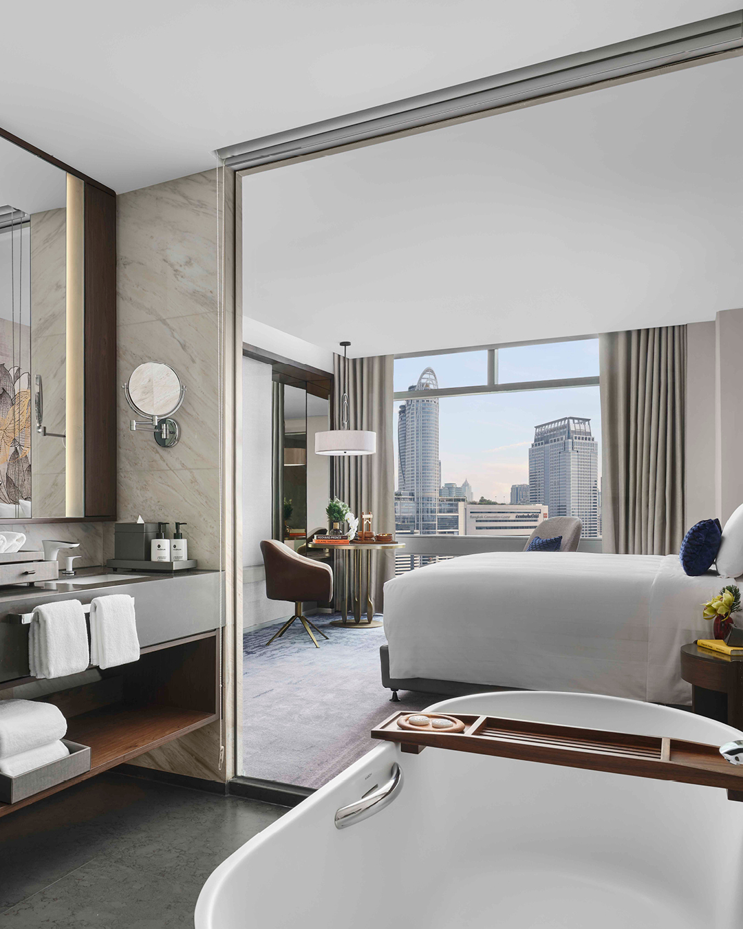 View of bed and window from bathroom with large mirror and tub in a room at Chatrium Grand Bangkok