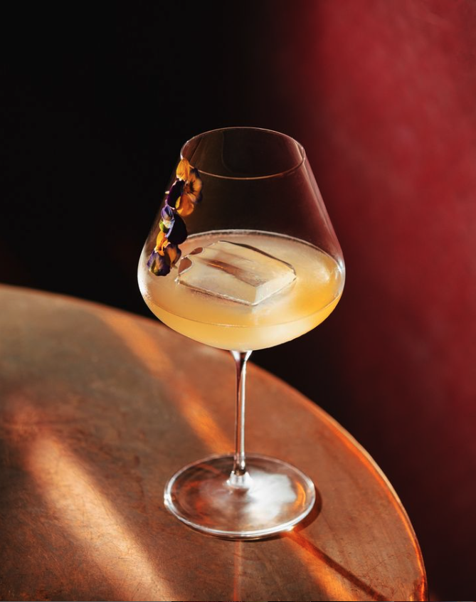 A Pop Yeh Yeh made with Brass Lion gin, sour plum, kiwi and apple at Republic cocktail bar in Singapore, with edible flowers garnishing the glass.