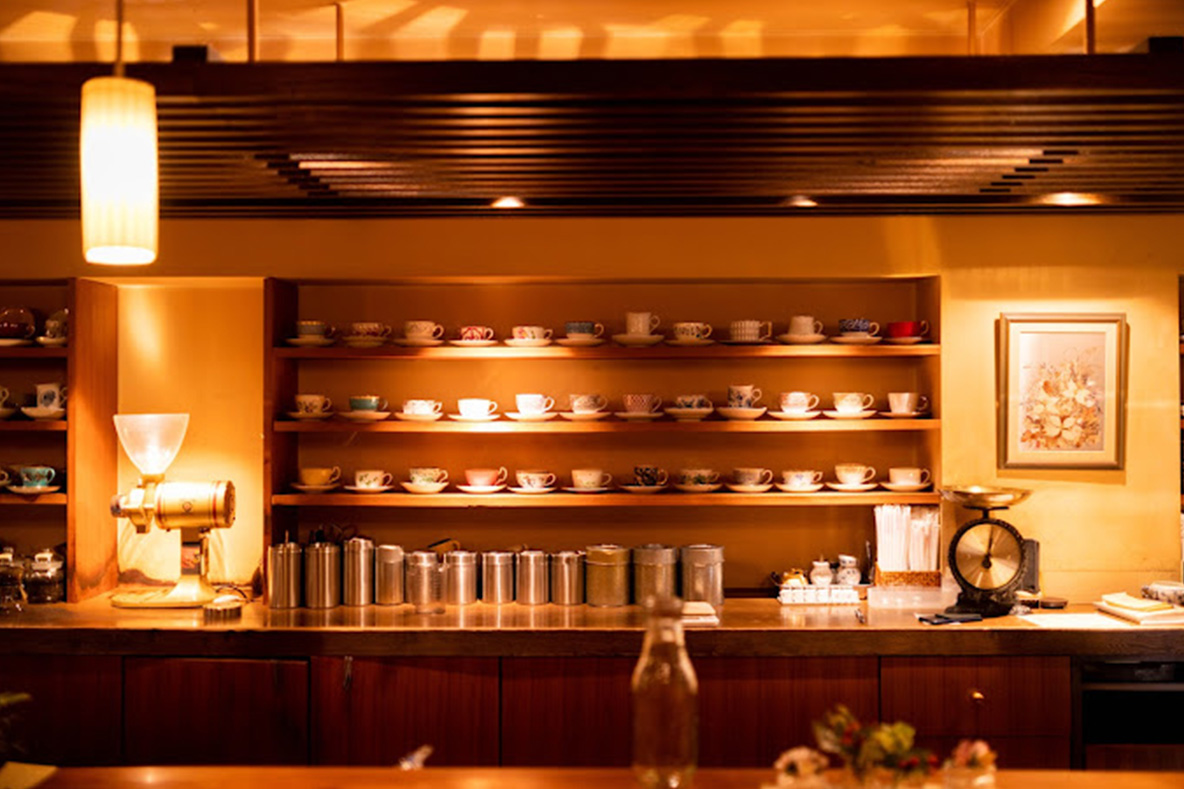 Ceramuc mugs arranged on shelves behind a wooden bar at Charcoal Roast Coffee RIN, Tokyo.