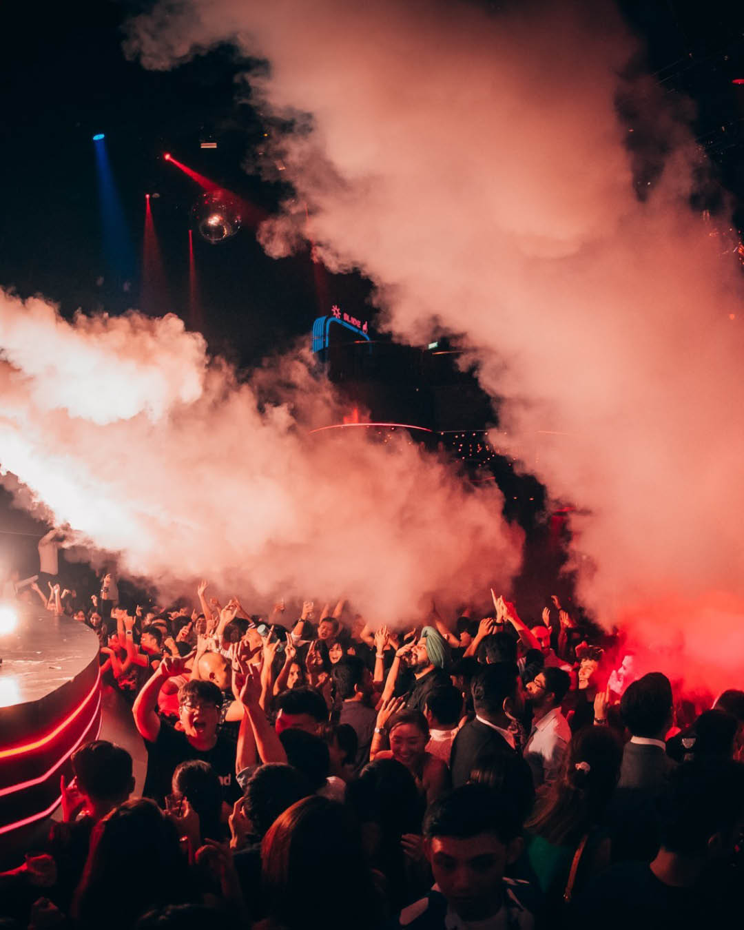 Crowds cheering with red flares smoking above their heads at Marquee, Singapore.