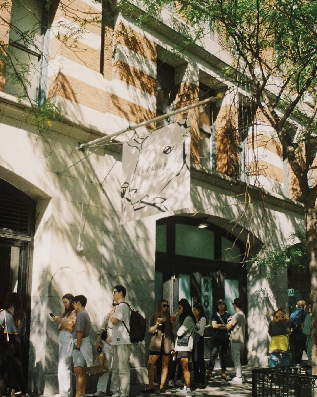 A street view outside La Cabra coffee shop in New York, where customers queue beneath La Cabra's sign.