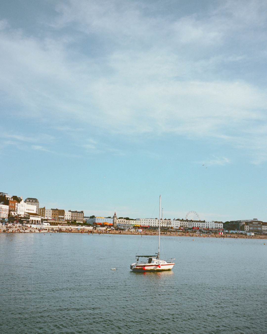 A calm coastal scene with a boat in a beach and colourful buildings.