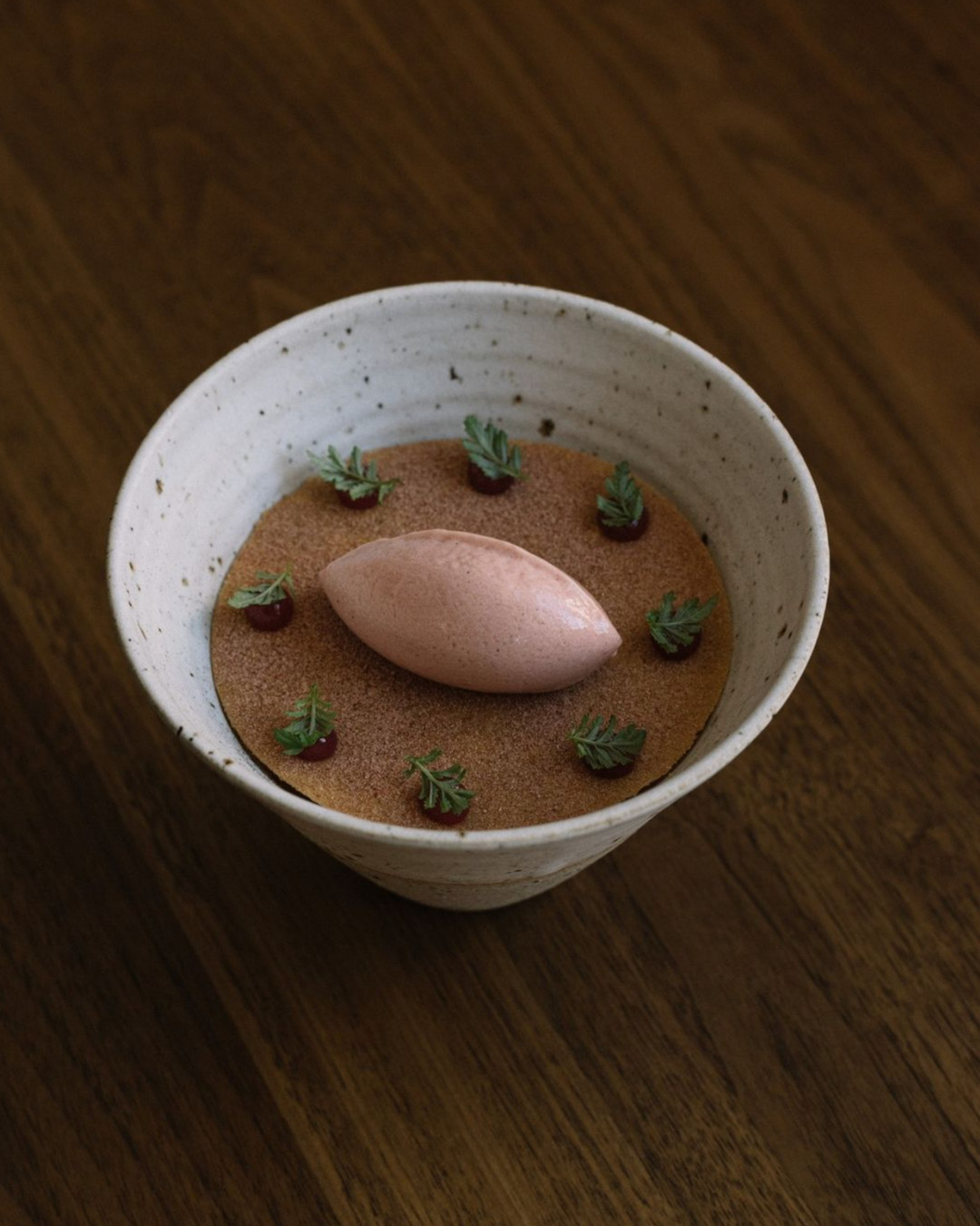 A dessert made of rhubarb, yogurt and lemon thyme⁠, served in a small white ceramic bowl on a wooden tabletop at Ark.