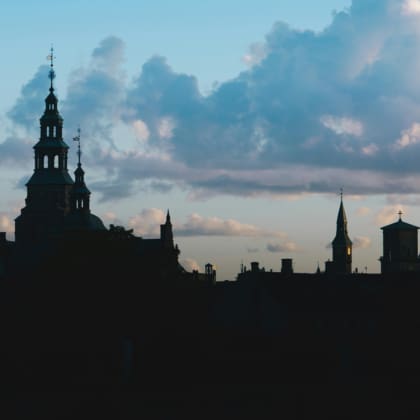 Copenhagen skyline silhouette against a gradient sky with clouds, creating a serene and contemplative mood.