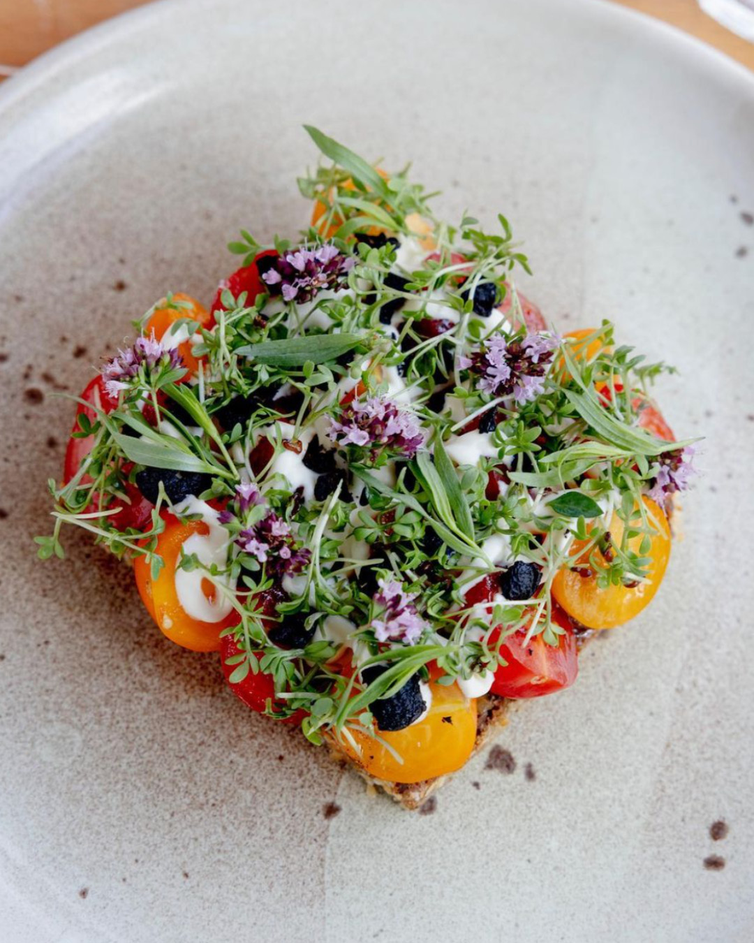 A colourful, flowery smørrebrød served on a white plate at Judie restaurant in Copenhagen.