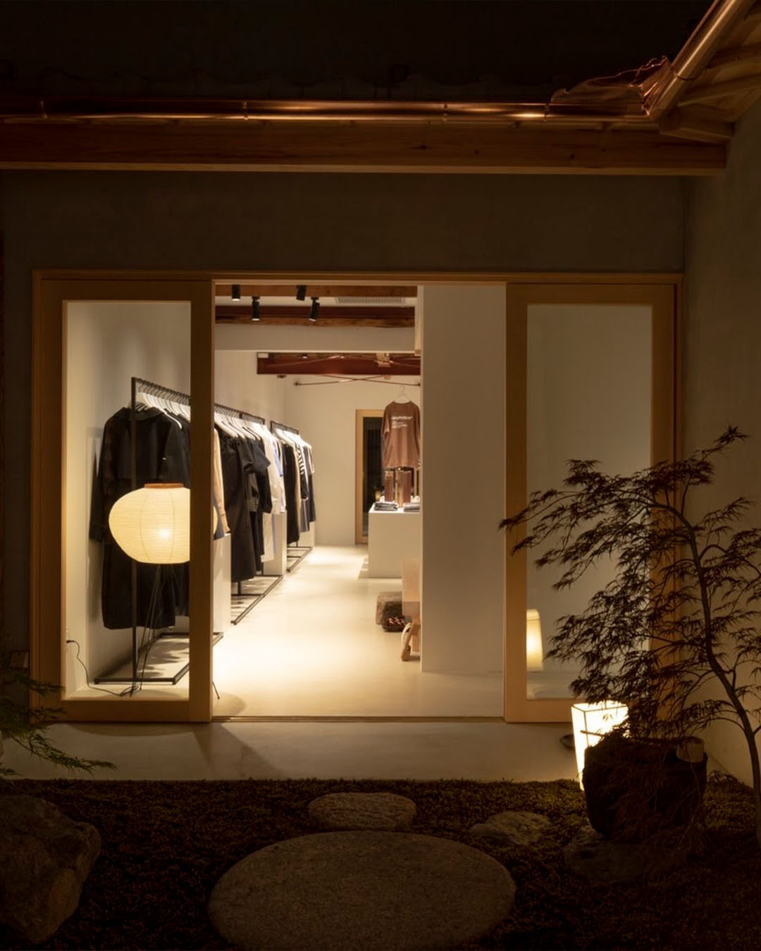 Inside Graphpaper shop in Kyoto, clothes hang on one clothes rail in a minimal interior set around a traditional courtyard.