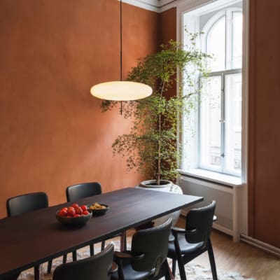 Terracotta walls, a pot plant and a long black table with black chairs against it in a meeting room at SOHO co-working office in Copenhagen.