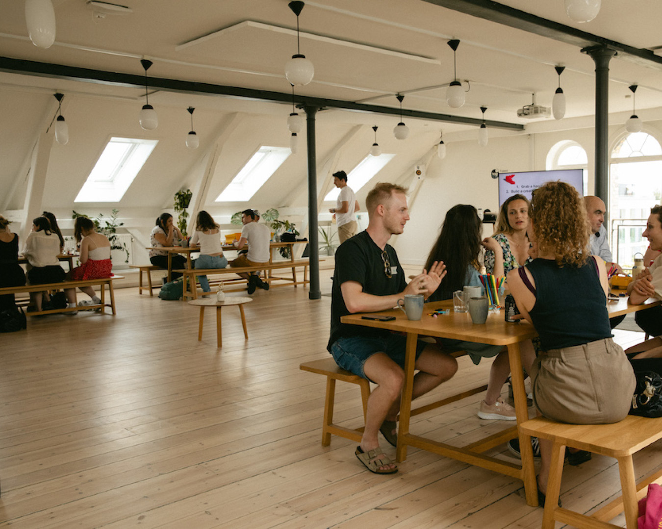 People chat over tables at Talent Garden Denmark co-working space in Copenhagen.