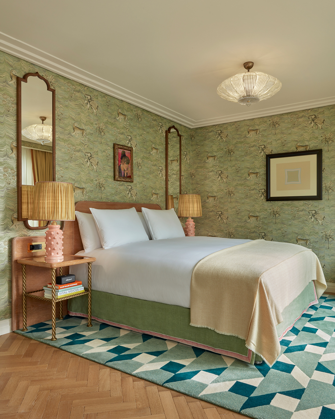 Elegant room at Broadwick Soho, London, featuring a stylish bed, vintage mirrors, and a geometric patterned rug against a textured green wall.