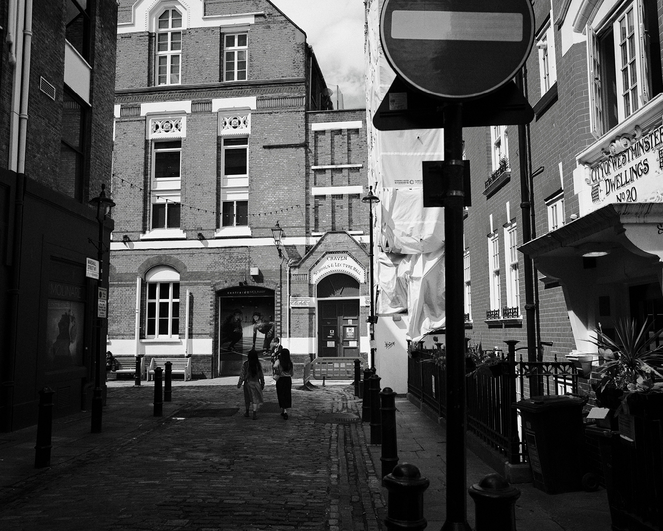 View of Marshall Street in Soho, London, featuring historic brick buildings and pedestrians walking along a cobblestone path.