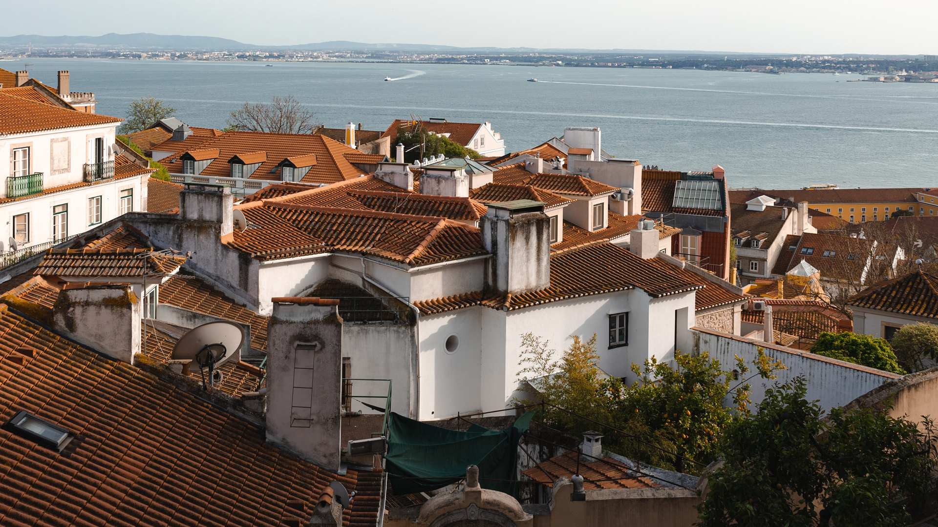 Views over Lisbon rooftops to the Tagus River, Lisbon. Image courtesy of Home Exchange