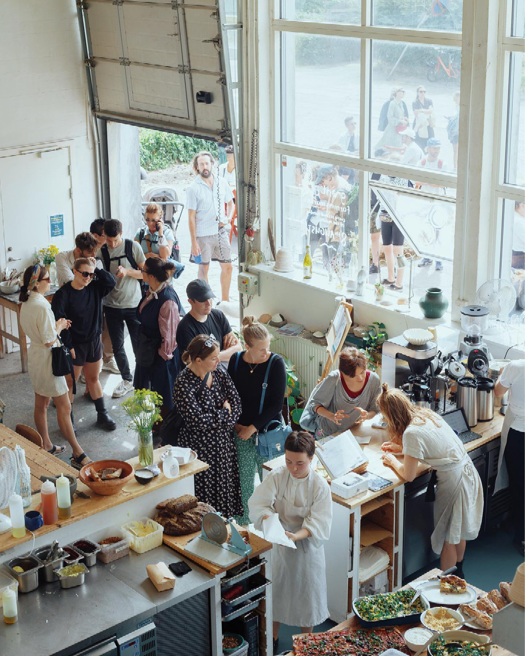 A line of people queue in Lille Bakery, a high-ceilinged bakery in a warehouse in Copenhagen's Refshalevej area of the harbour.