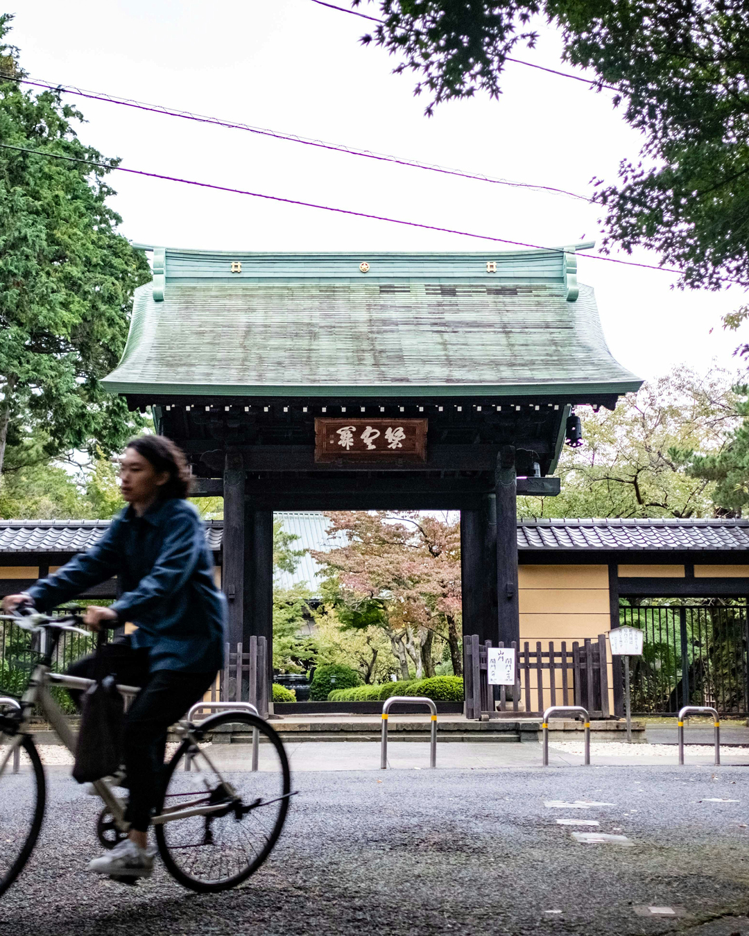 A cyclist rides past a traditional gateway in Kyoto.